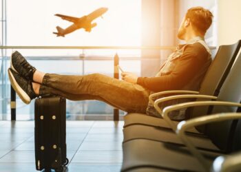 Traveler with luggage watching an airplane before an international healthcare trip
